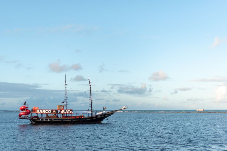 A picturesque pirate ship sails on the tranquil waters of Arraial d'Ajuda, Bahia, Brasil.