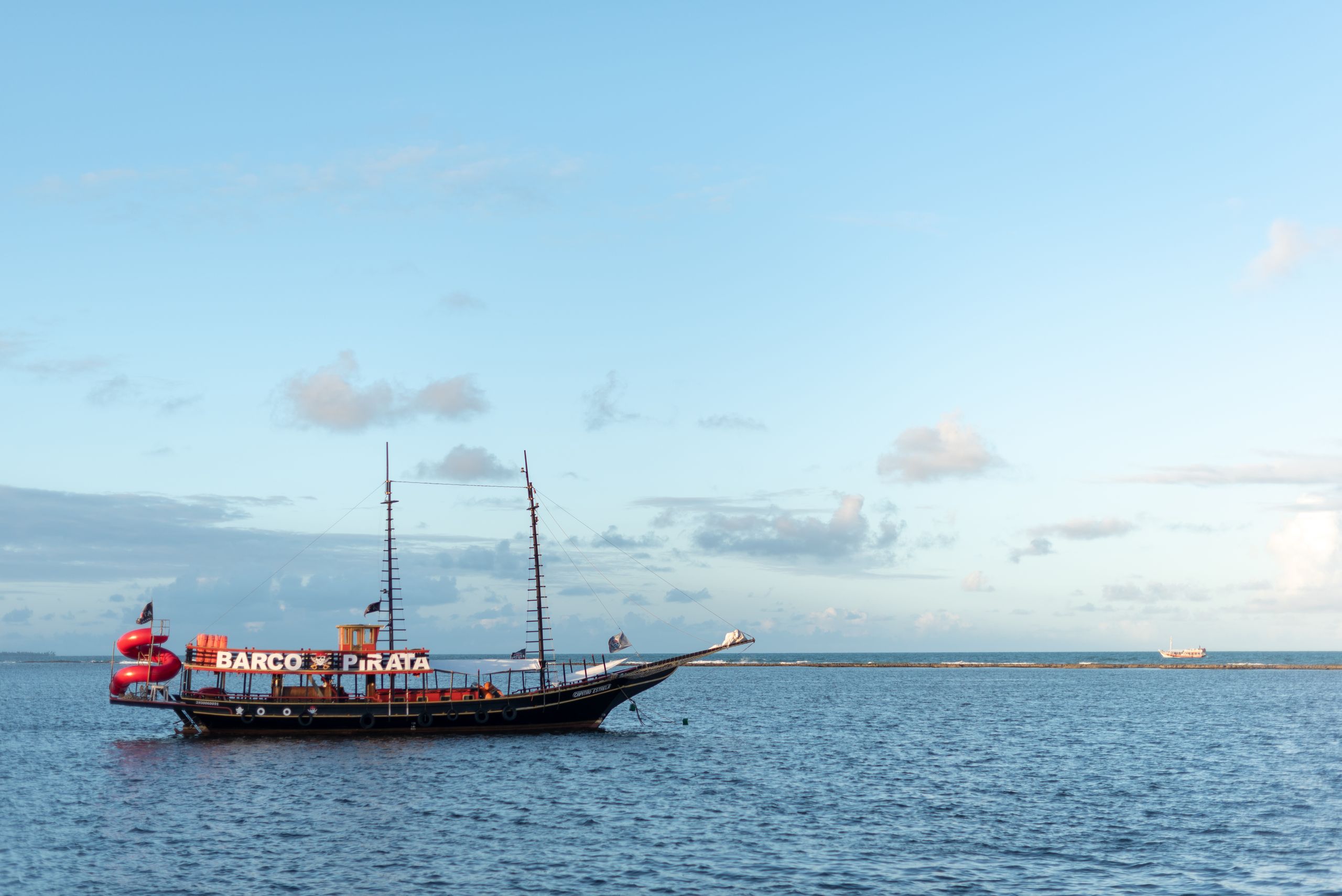 A picturesque pirate ship sails on the tranquil waters of Arraial d'Ajuda, Bahia, Brasil.